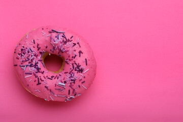 Sweet glazed donut decorated with sprinkles on pink background, top view and space for text. Tasty...