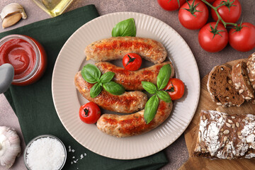 Flat lay composition with tasty homemade sausages, basil leaves and tomatoes on brown table