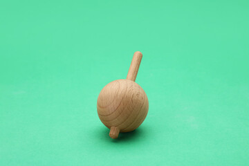 One wooden spinning top on green background. Toy whirligig