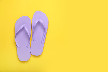 Stylish violet flip flops on yellow background, top view. Space for text