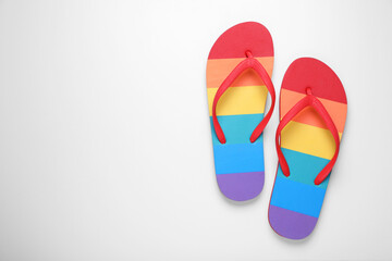 Stylish rainbow flip flops on white background, top view. Space for text - Powered by Adobe