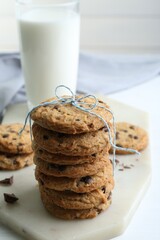 Tasty chocolate chip cookies and glass of milk on white wooden table, closeup