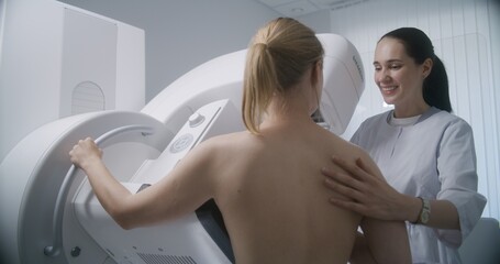 Hospital radiology room. Caucasian woman stands during mammography screening procedure. Female...
