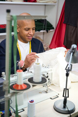 Pleased young tailor inspecting seams pinned on gown