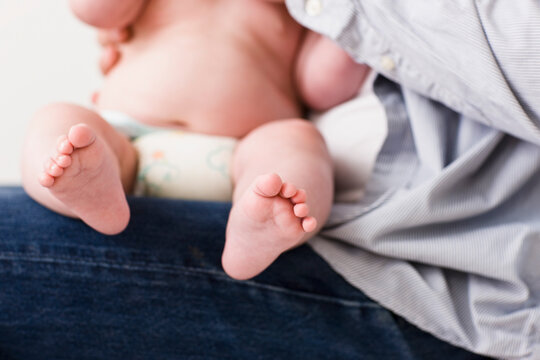Man legs with newborn baby on his lap
