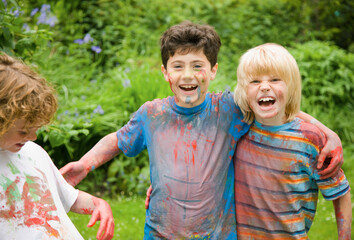 Young boys covered in watercolor paint laughing in a garden
