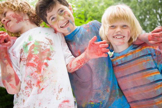 Young boys covered in watercolor paint laughing in a garden
