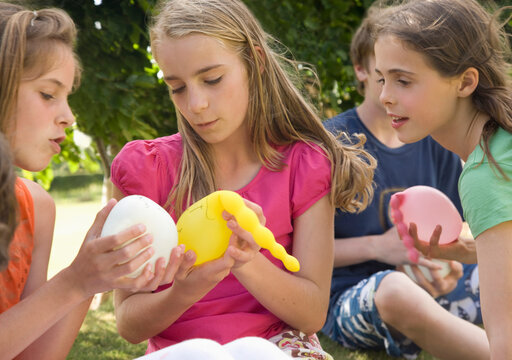 Girls holding balloons full of water
