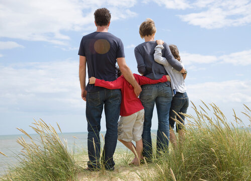 Back view of a family standing on a beach
