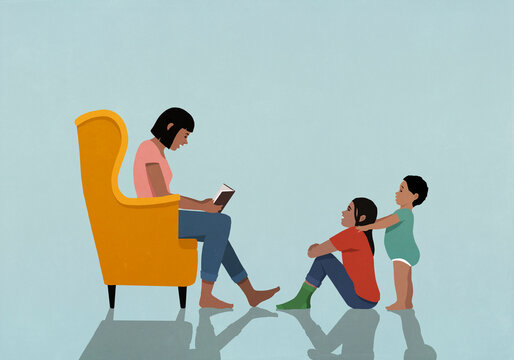 Mother in armchair reading book to daughter and son at home

