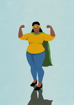 Portrait happy, confident woman flexing biceps in superhero cape and mask
