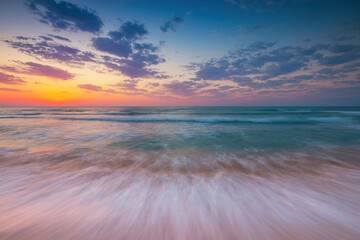 Fototapeta na wymiar Ocean sunrise over beach shore and waves. The sun is rising up over sea horizon