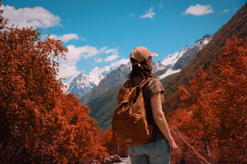 Girl with a backpack stands with her back and looks into the distance at the mountains. Active lifestyle, travel that inspires. Autumn landscape