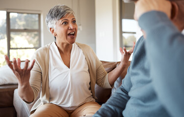 Divorce, fight and senior couple on a sofa angry, shouting and frustrated in their home together....