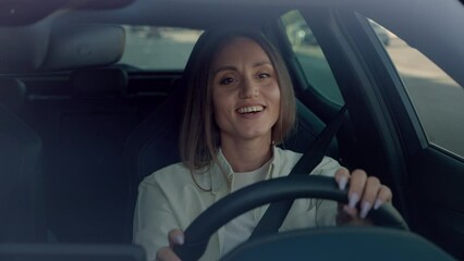 Stylish brunette enjoying music while driving car