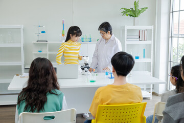 Hiring elderly working employment, Senior teacher happy teaching in science laboratory class with group of Asian cheerful students, pupil girl volunteer standing in front of classroom using microscope