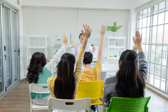 Group Of Asian Students Teenager In Private School Raising Hands Up Answering Science Teacher In Classroom, Pupils Participate With Senior Teacher In Lab Class, School Kids Children Have Fun Studying