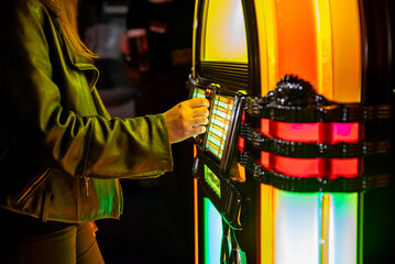 woman hand pushing buttons to play song on old Jukebox, selecting records