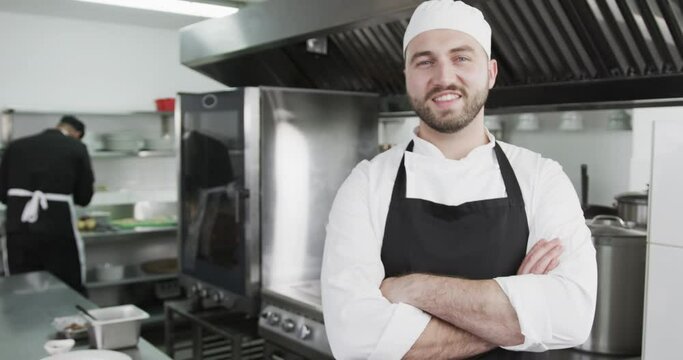 Caucasian male chet smiling and having arms crossed in kitchen, slow motion