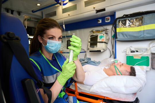 Employee of field team in ambulance prepares syringe with medicine
