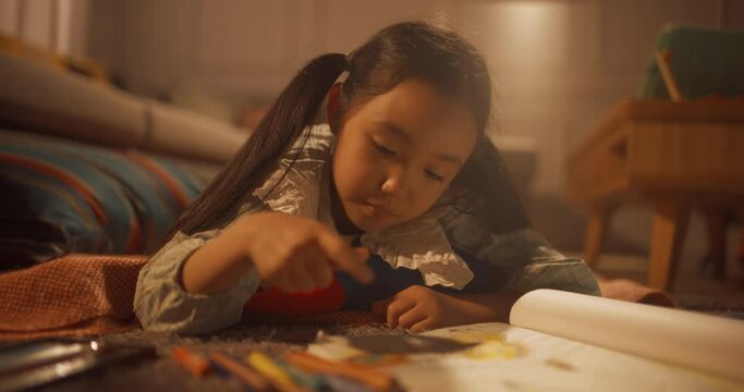 따뜻한 조명이 비치는 거실 바닥에 누워 그림을 색칠하는 소녀의 영상, 시네마틱 샷