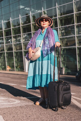Tourist senior woman standing in front of the airport looking straight in the afternoon