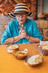 tourist senior woman excited for the delicious food in colorful indian restaurant
