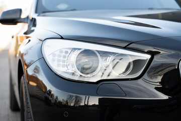 Close up of headlight lamp of luxury auto in black color. Modern and expensive city car with premium details in exterior design