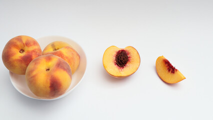 Fresh ripe peaches in a white plate, half and a quarter of a peach on a white background. Organic vitamins for dessert. Delicious and healthy food.