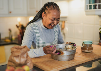 Fototapeta na wymiar Happy senior african woman cooking christmas cookies inside house kitchen