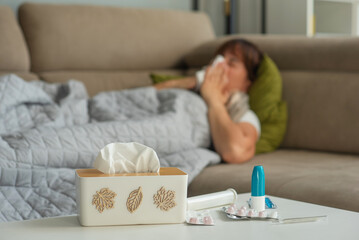 Ill sick middle aged woman sneezing blowing running nose holding tissue sit on bed, upset mature...