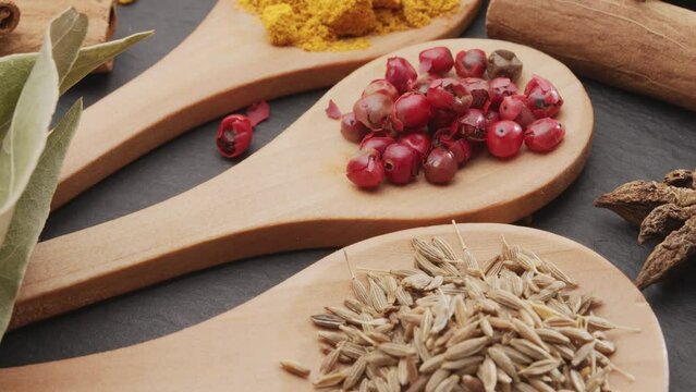 Various types of spices on wooden spoons slowly move along the frame, a great food background for your projects.