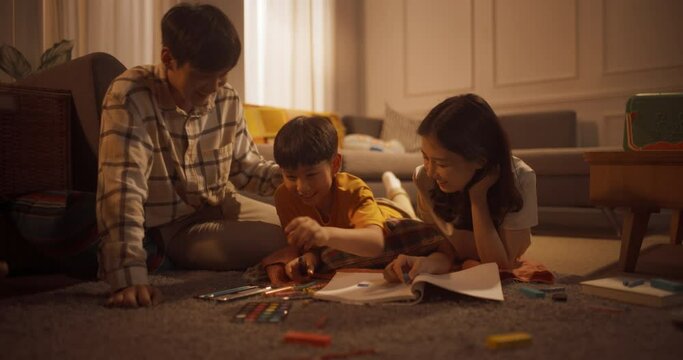 바닥에 엎드려 아들이 공책에 그린 그림을 웃으며 칭찬하는 엄마와 아빠