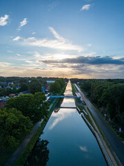 Behold the picturesque town of Rijkevorsel as the sun's first light bathes its historic drawbridge in a warm and enchanting glow. This stunning aerial view captures the timeless beauty of the