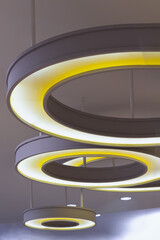 The hanging rounded ceiling mounted light fixtures with modern LED light bulb. See the yellow circular ring shaped lamps hang under ceiling, Architecture and interior design round lights on ceiling.