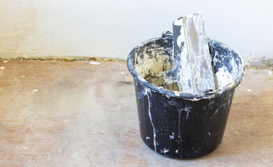 Renovation essentials: Black putty bucket with a large spatula, smeared with fresh putty. Perfect...