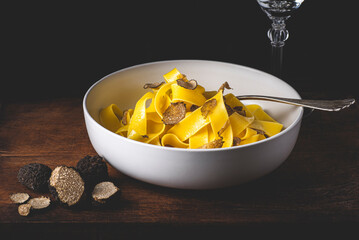 Pappardelle pasta with black truffle mushrooms. Tagliatelle or pappardelle al tartufo - Italian autumn fresh recipe with black truffle, rustic dark style, magic light. Autumn gourmet cuisine 