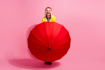 Full length photo of shiny cheerful woman dressed rain coat holding parasol empty space isolated pink color background © deagreez