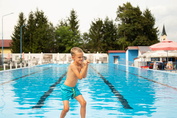 A seven-year-old boy of European appearance poses and makes faces near the pool.