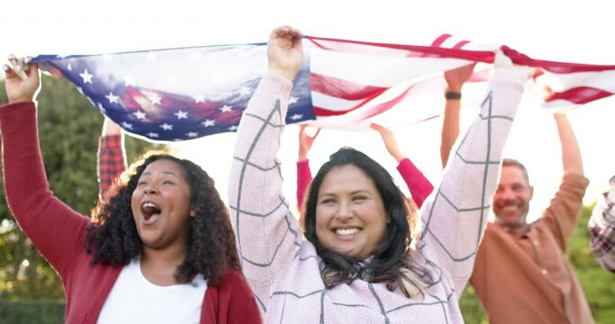 Happy diverse male and female friends dancing with flags in sunny garden - Powered by Adobe