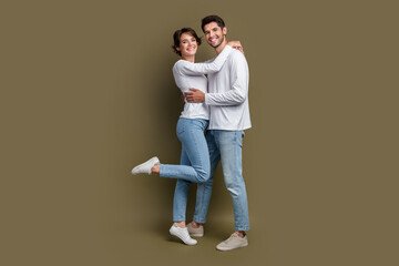 Full length photo of pretty cheerful married couple wear white shirts embracing isolated brown color background