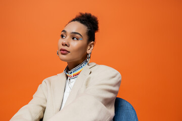 Obraz premium beautiful young model in chic street clothing vibrant makeup and hoop earrings looking away