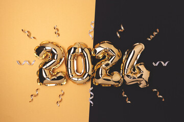 2024 inflatable foil balloons and ribbons confetti on a black and gold background. New Year festive...