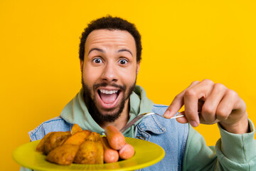 Portrait of impressed overjoyed person open mouth hold fork delicious fried potato sausage plate isolated on yellow color background