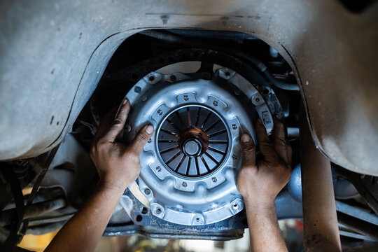 Mechanic's hand installing new clutch plate in car, clutch system, auto mechanic in garage,service clutch system.