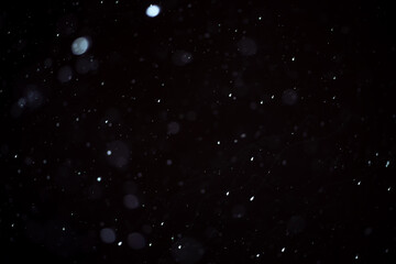 Background of flying snow on a dark background, soft focus snow texture