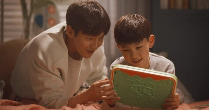 아이 방에서 태블릿으로 재미있는 교육 영상을 보는 아빠와 아들의 상반신 영상