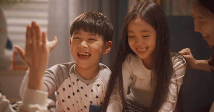 태블릿으로 비디오 게임을 즐기다가 승리하여 하이파이브를 하는 부모와 자녀