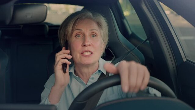 Aged blonde lady answering phone call while driving auto