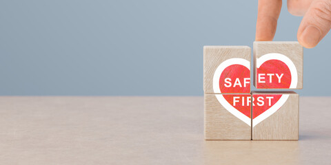 Safety first, heart shaped icon on wooden cubes in human hand. work safety, caution work hazards,...